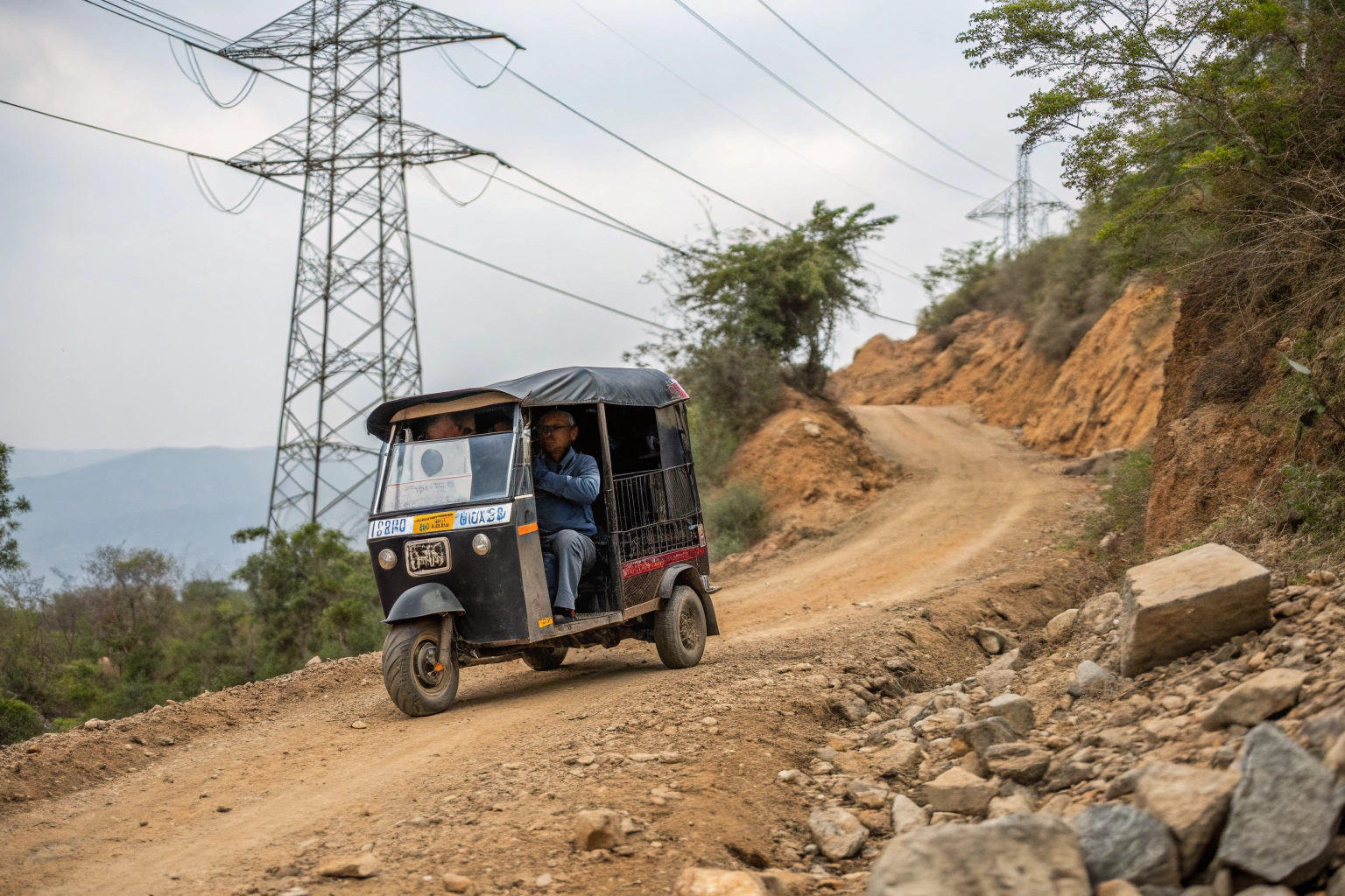 An electric tuk-tuk loaded with passengers driving on a rough road