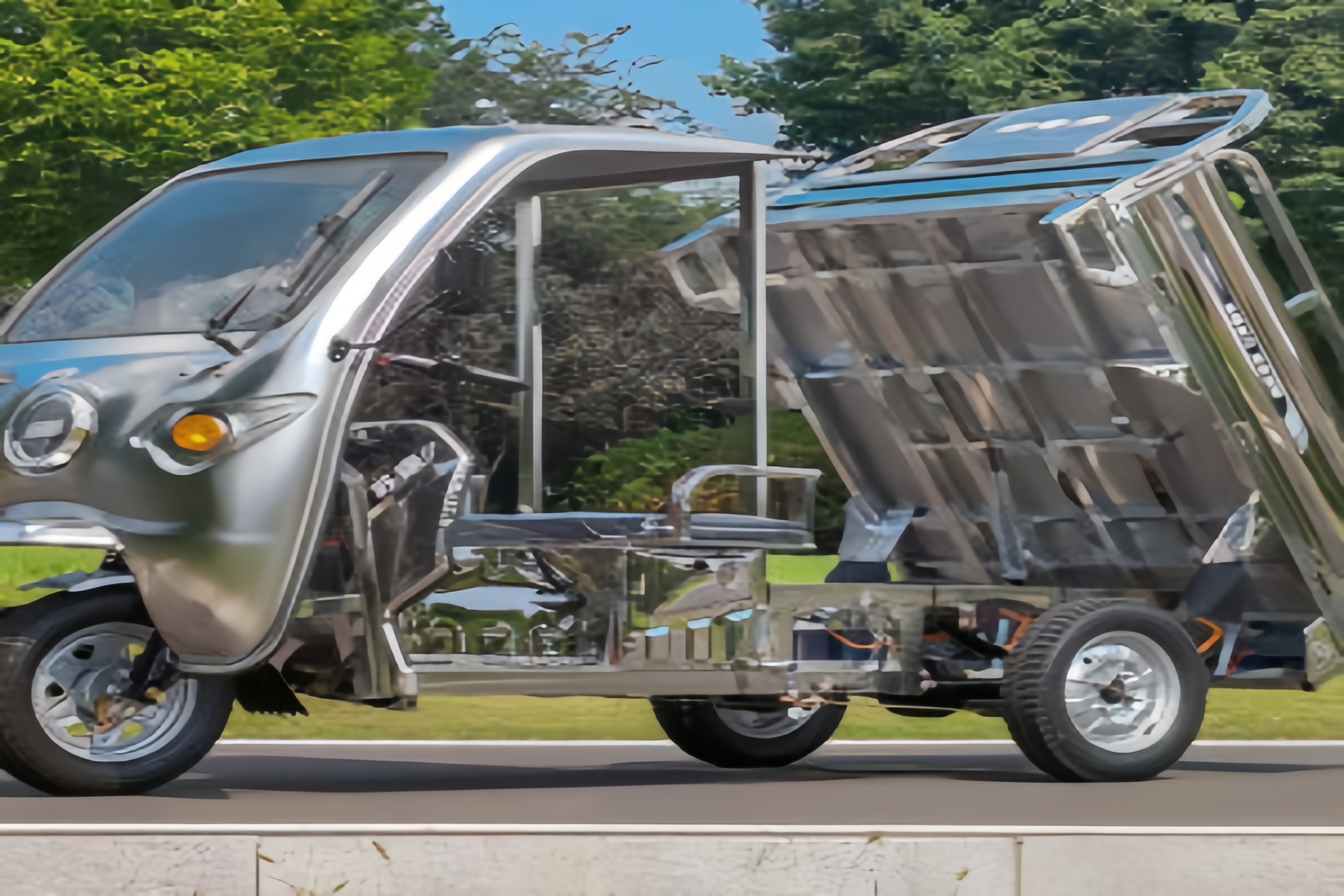 gleaming stainless steel electric cargo tricycle parked near a coastal area