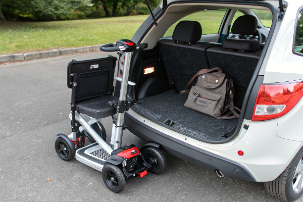 A person easily folding a mobility scooter to put in a car trunk