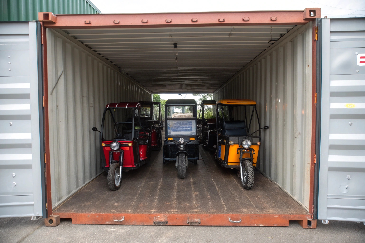 electric tricycles being loaded into a shipping container at a factory