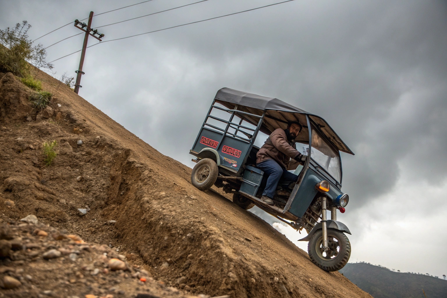 an electric cargo tricycle driving up a steep hill fully loaded with goods