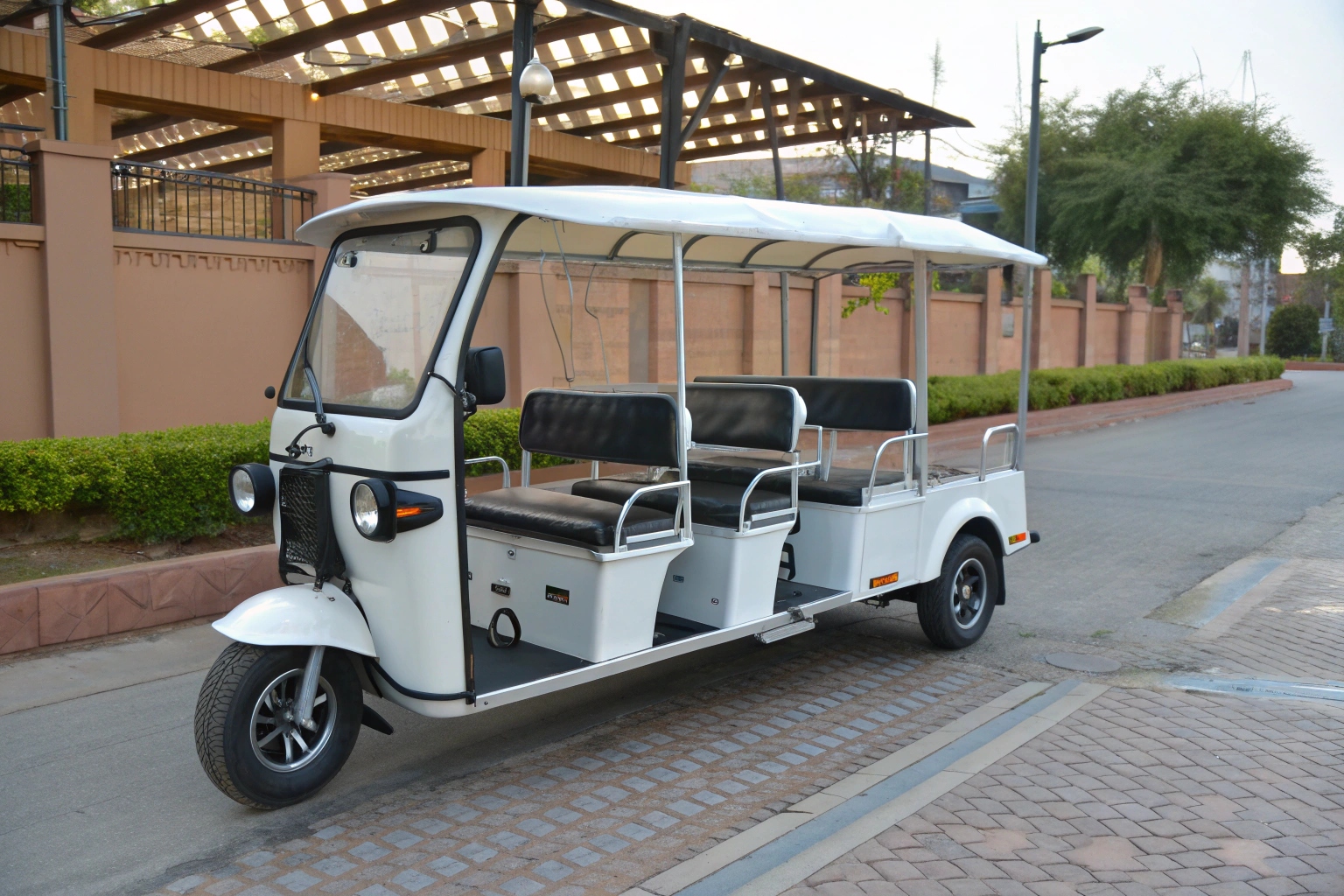 An extended electric tuk-tuk with side-facing benches for 6 passengers