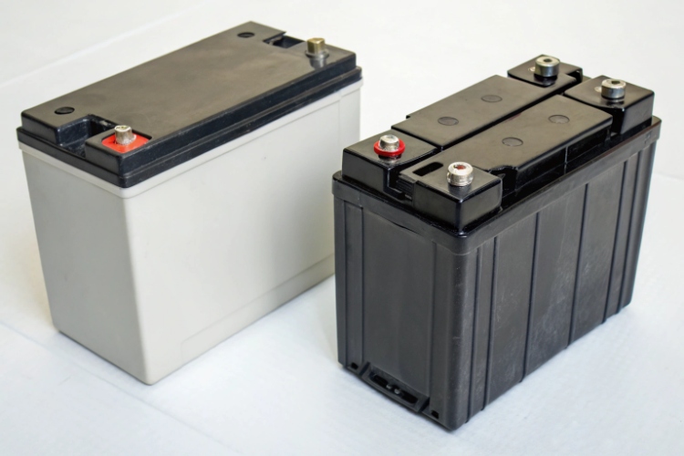 A technician choosing between a new lead-acid battery and a new LiFePO4 battery pack