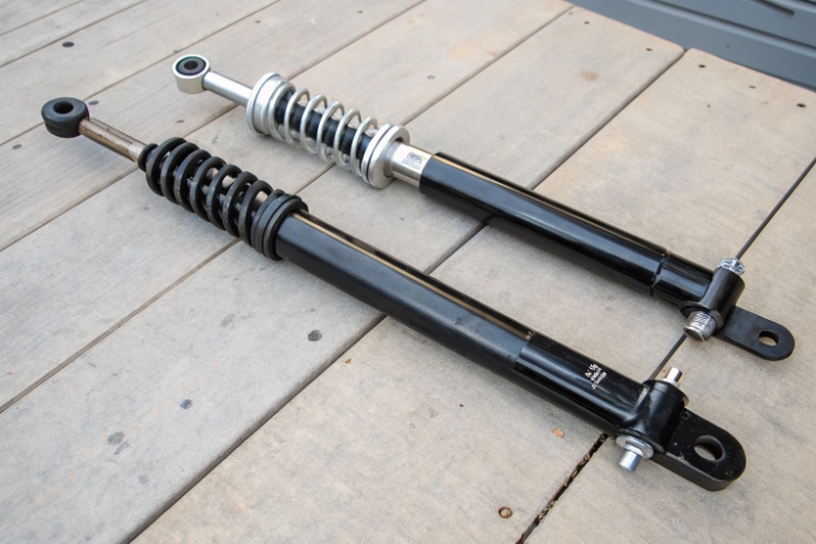 A mechanic easily replacing a simple front fork next to a more robust swing arm assembly